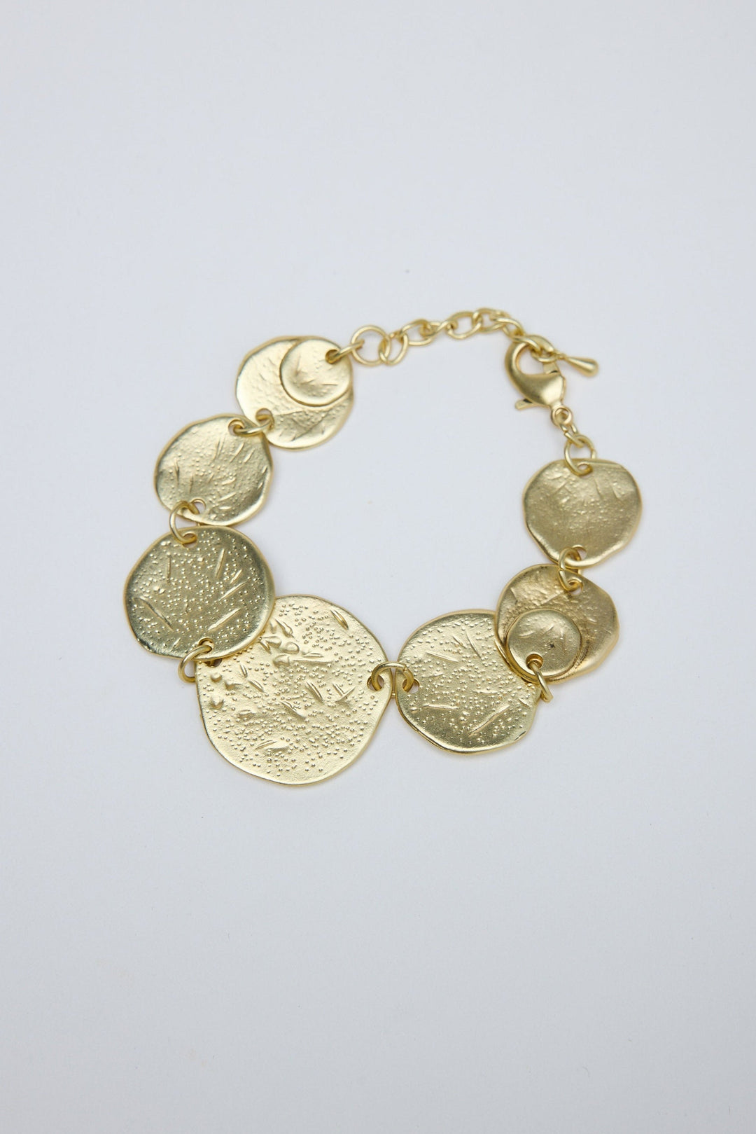 Gold bracelet with circular links on a light gray background