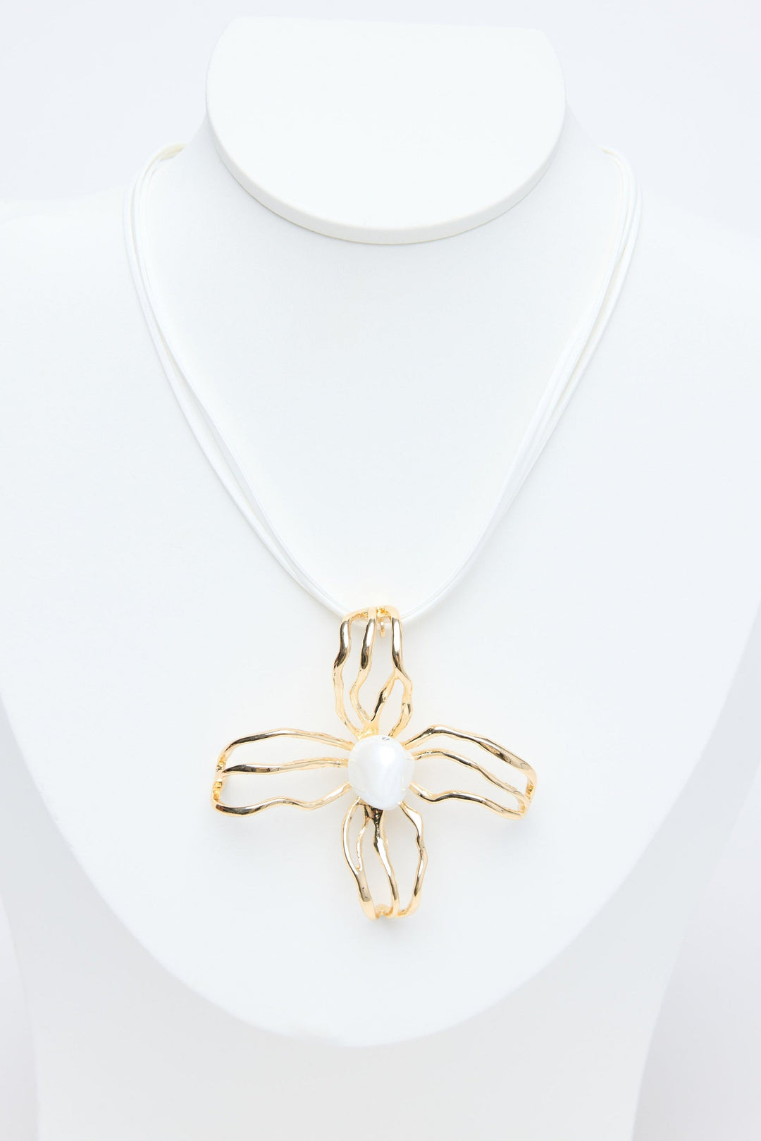 Gold flower pendant on a white necklace against a white background
