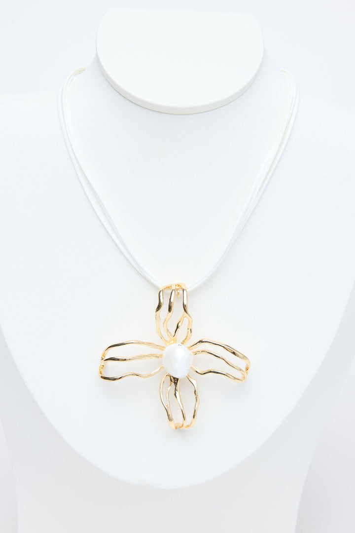 Gold flower pendant on a white necklace against a white background