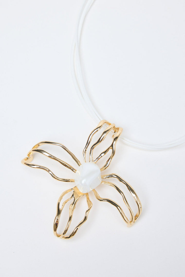 Gold flower-shaped pendant with a pearl on a white background