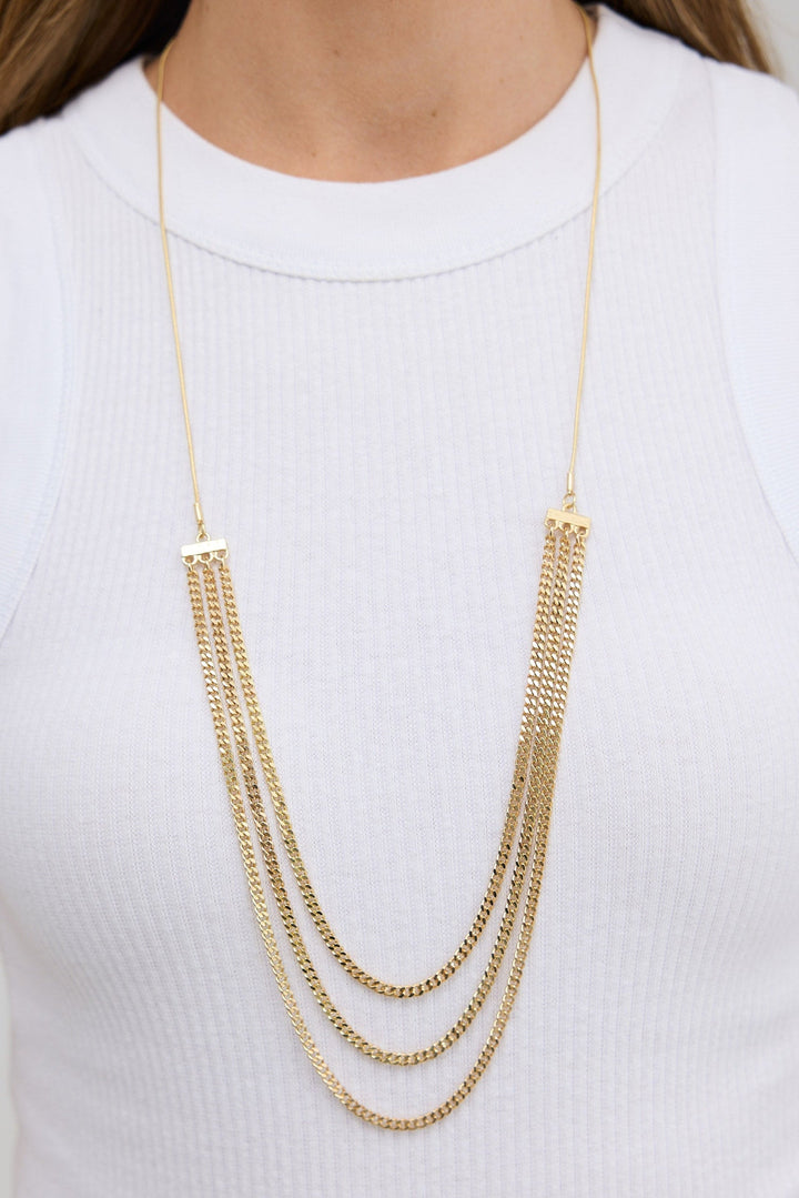 Gold chain necklace worn by a person on a white background
