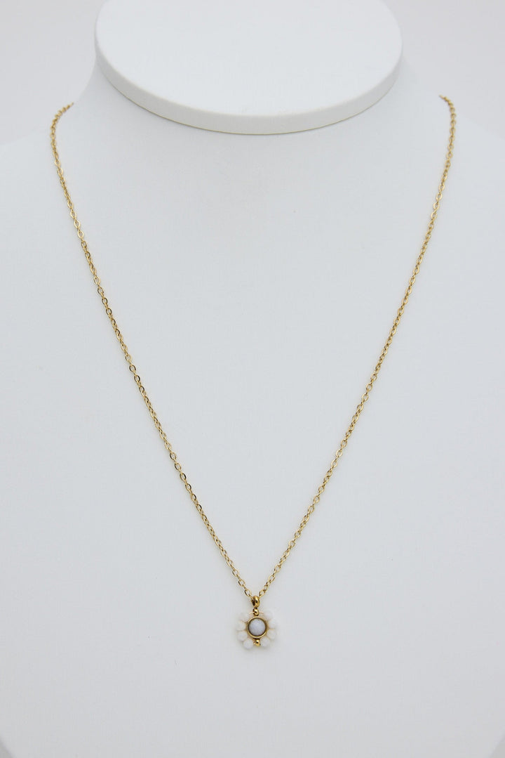 Gold necklace with a small pendant on a white mannequin bust