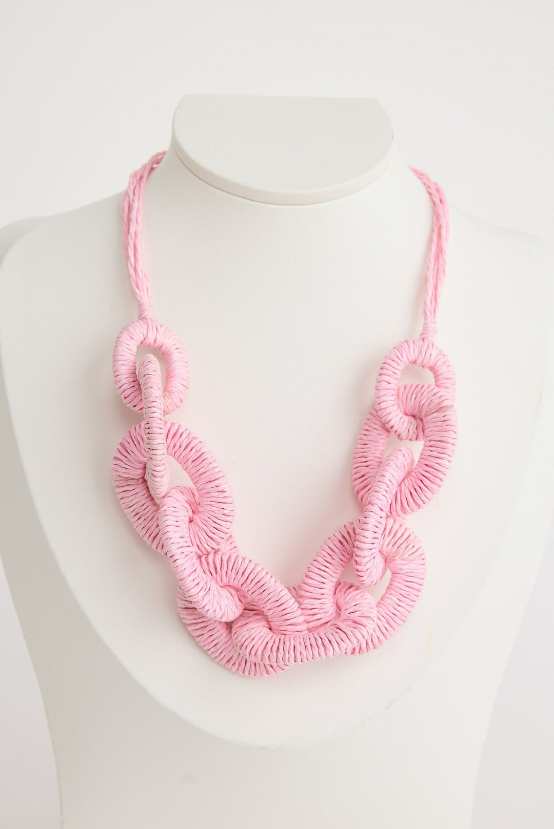 Pink knitted necklace on a mannequin with a white background