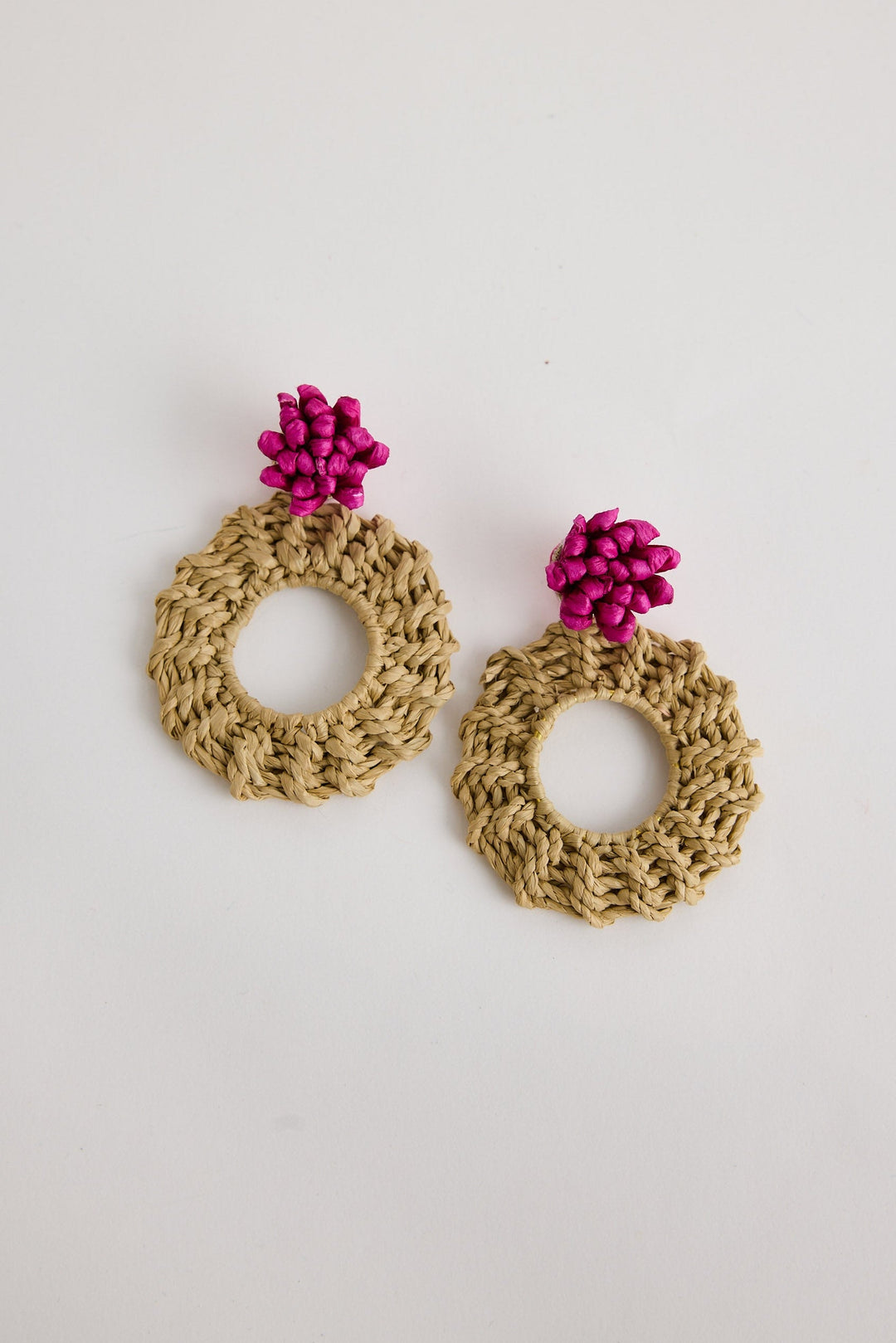 Crocheted earrings with pink floral tops on a light gray background