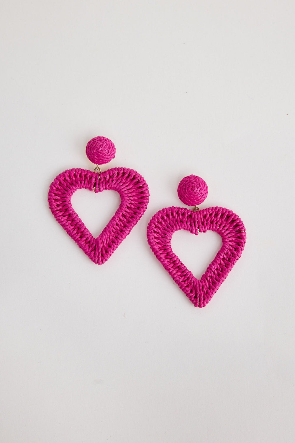 Pink heart-shaped earrings on a light gray background