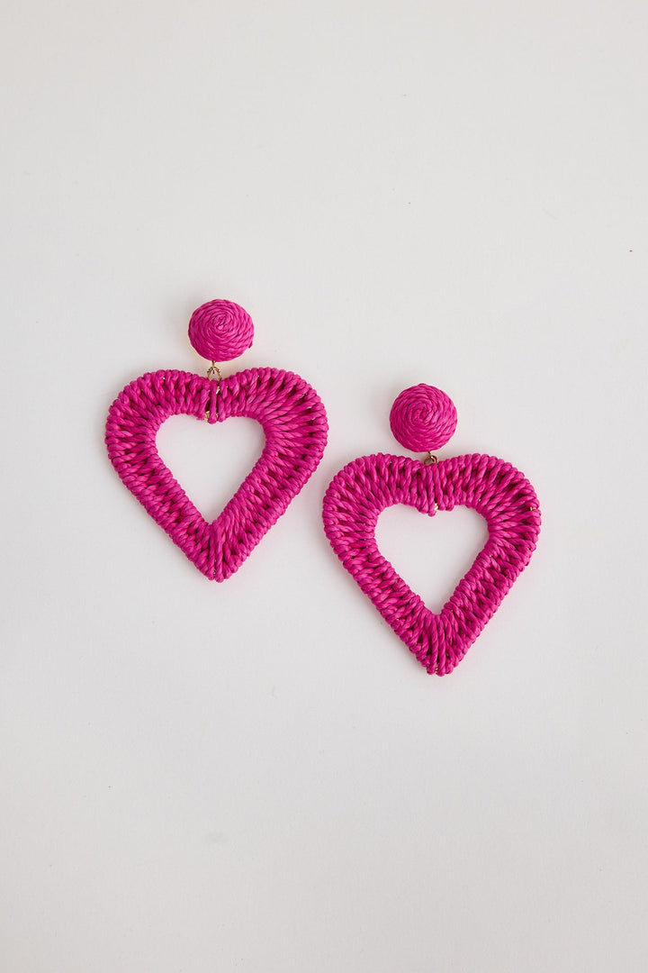 Pink heart-shaped earrings on a light gray background