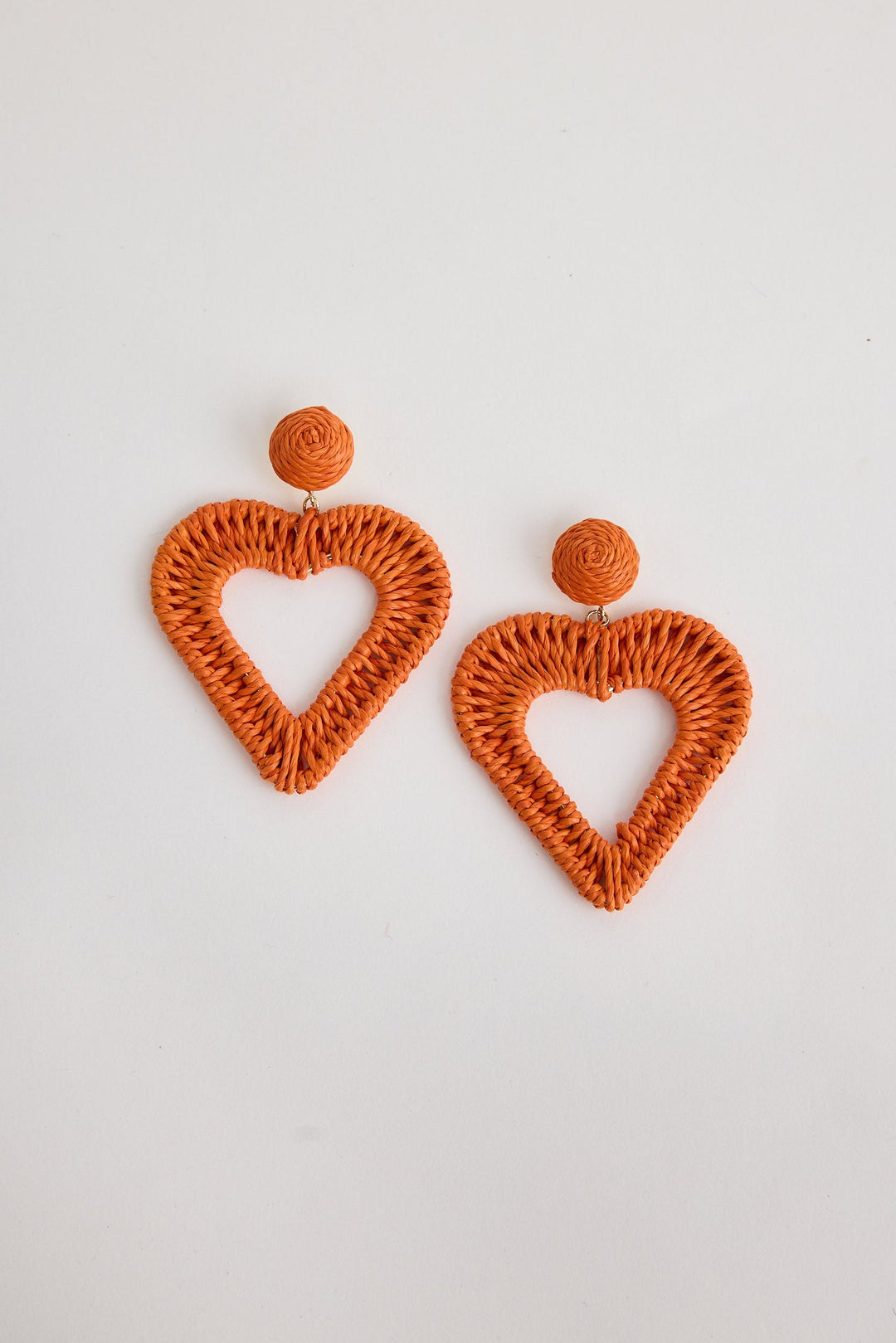 Orange heart-shaped earrings on a light gray background