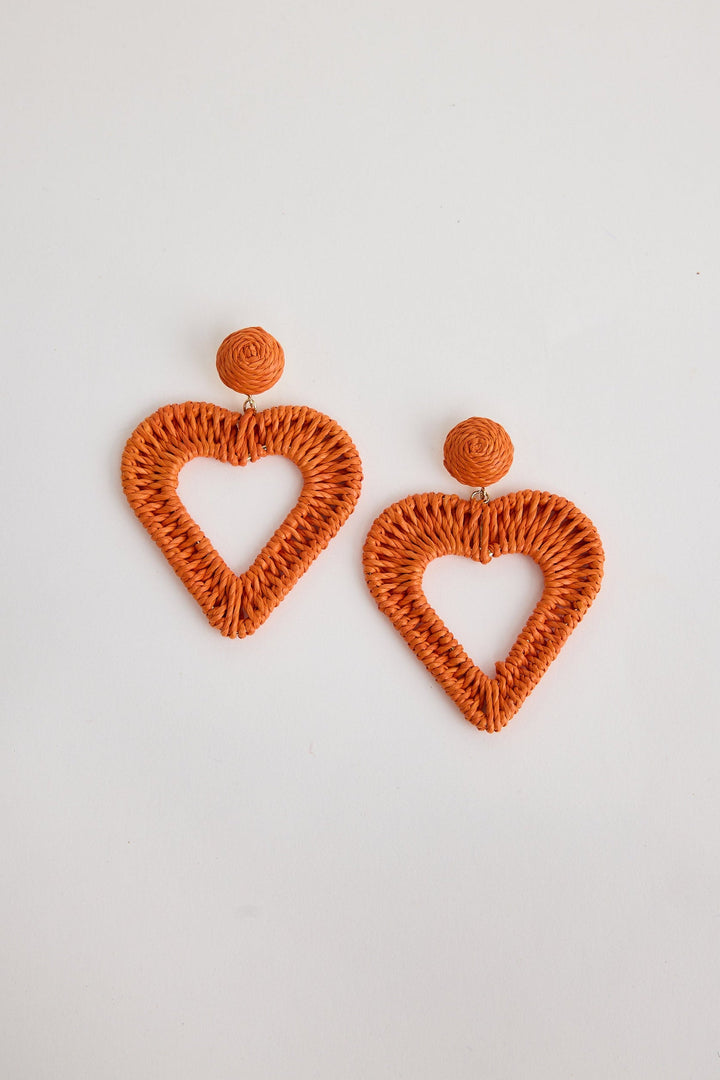 Orange heart-shaped earrings on a light gray background
