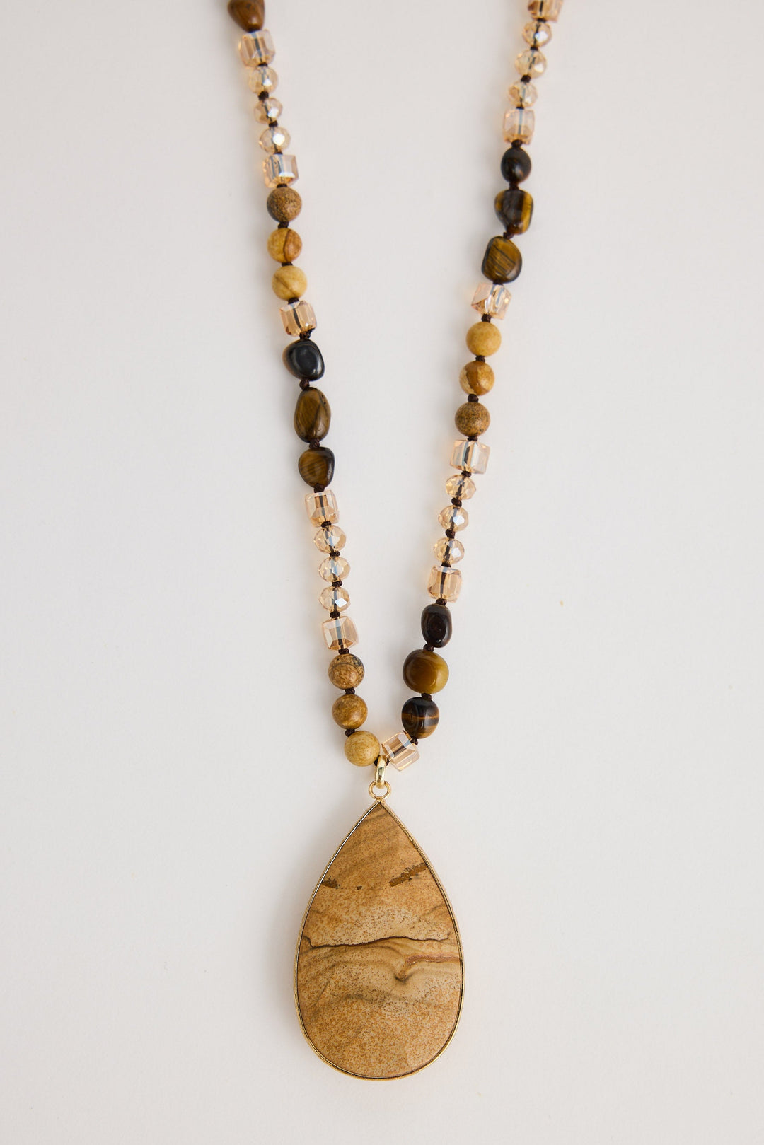 Necklace with teardrop pendant and beaded chain on a light background