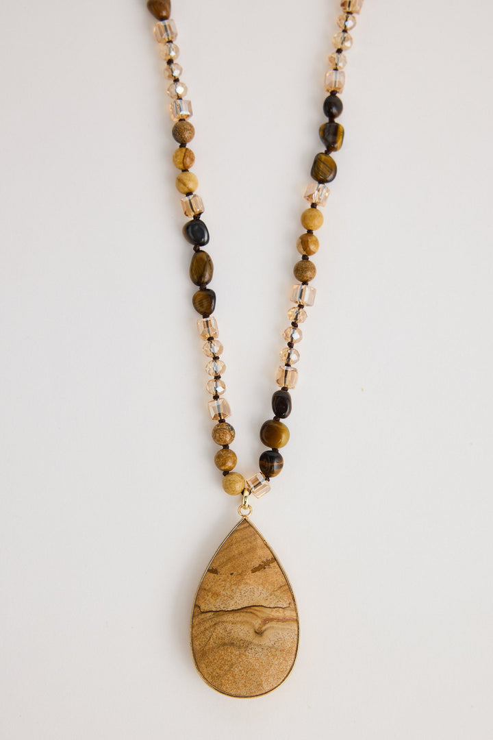 Necklace with teardrop pendant and beaded chain on a light background