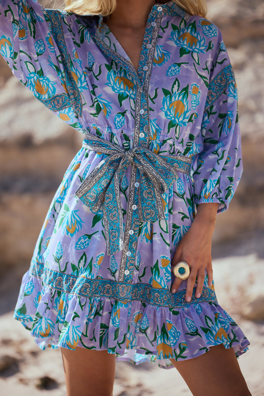 Person wearing a purple floral dress on a beach