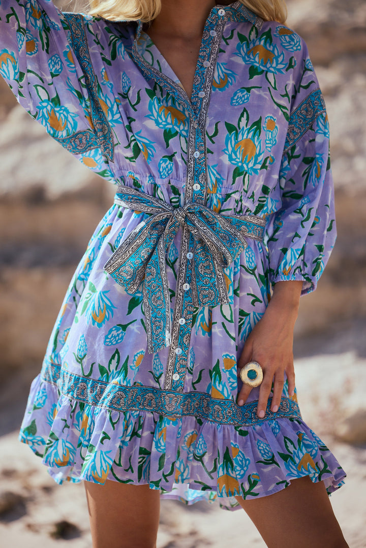 Person wearing a purple floral dress on a beach