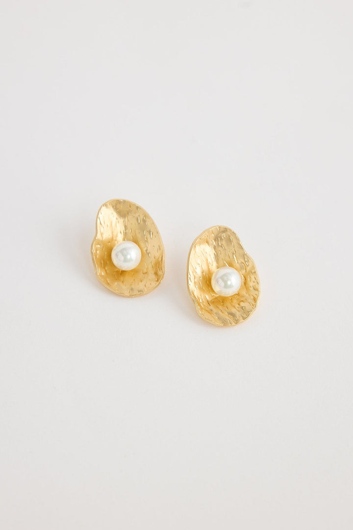 Gold earrings with pearl centers on a light gray background