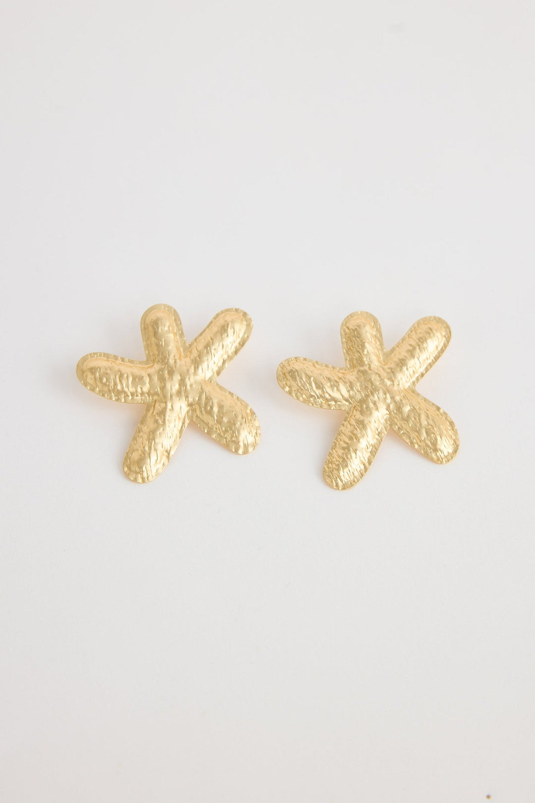Gold starfish-shaped earrings on a white background