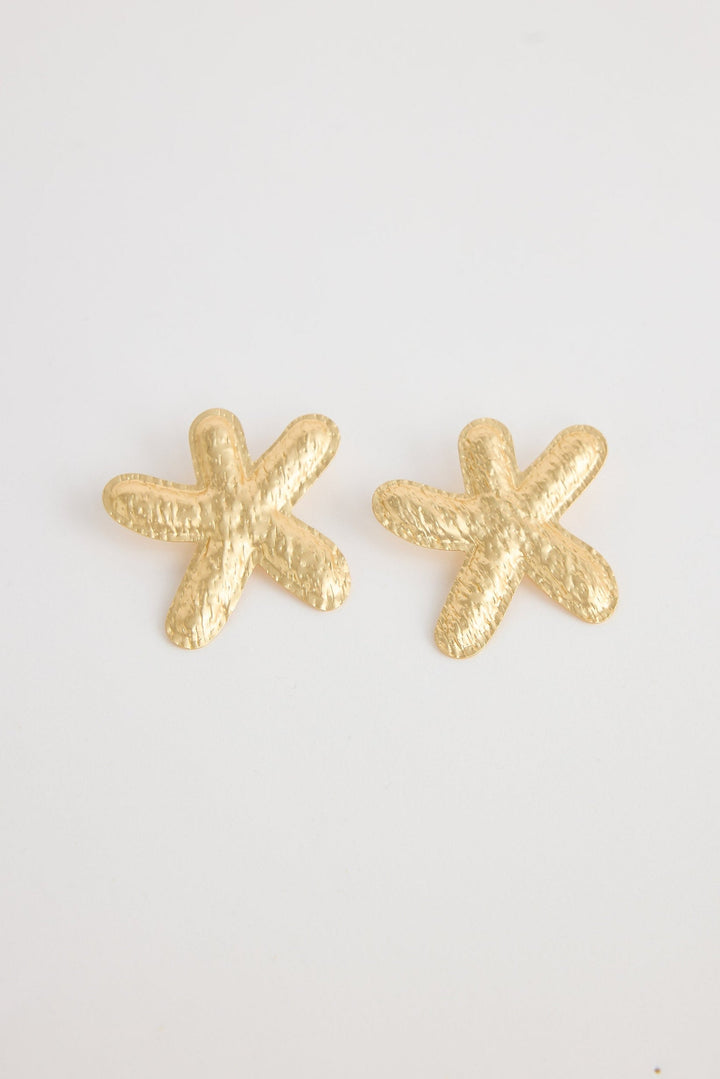 Gold starfish-shaped earrings on a white background