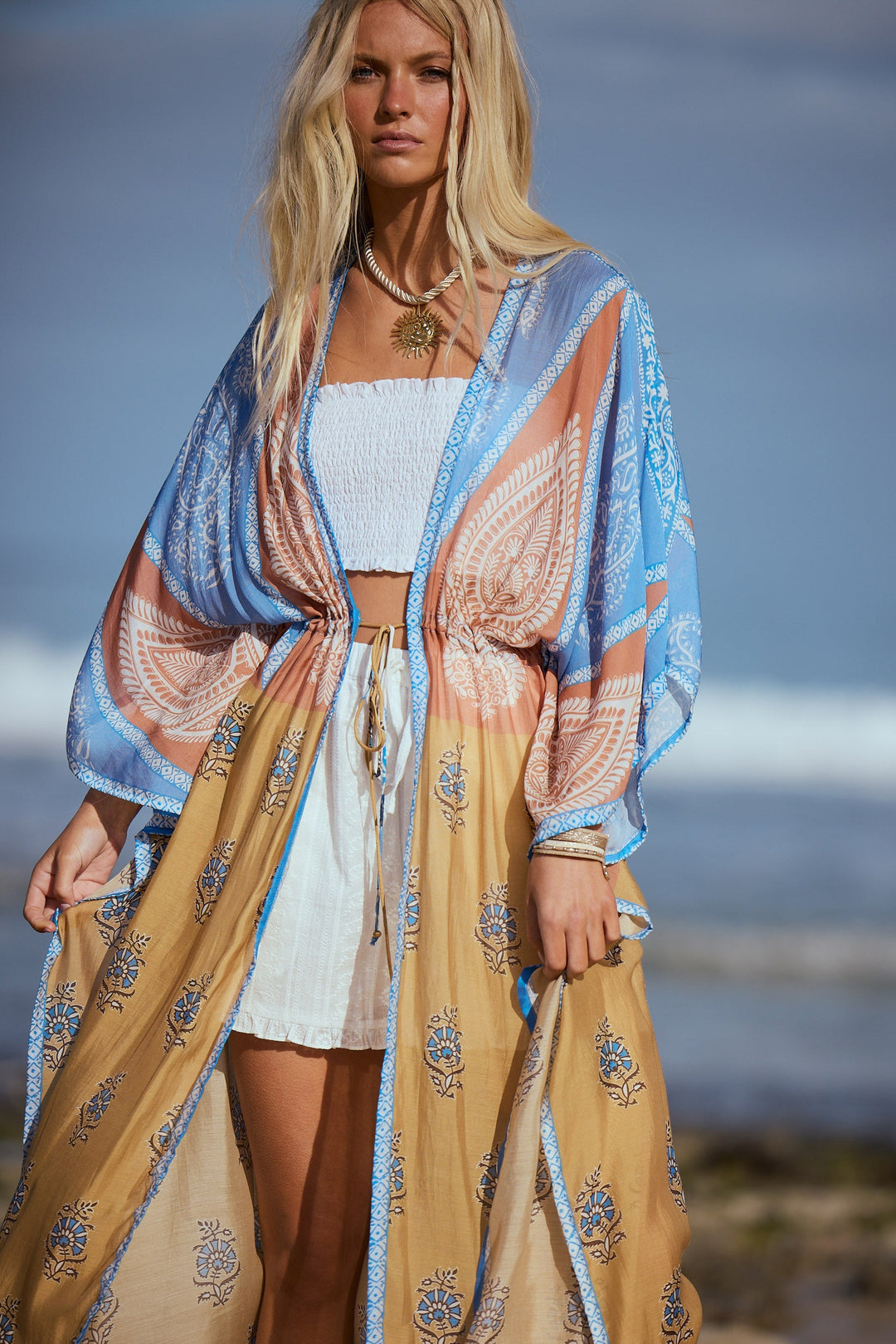 Woman wearing a patterned kimono standing on a beach.