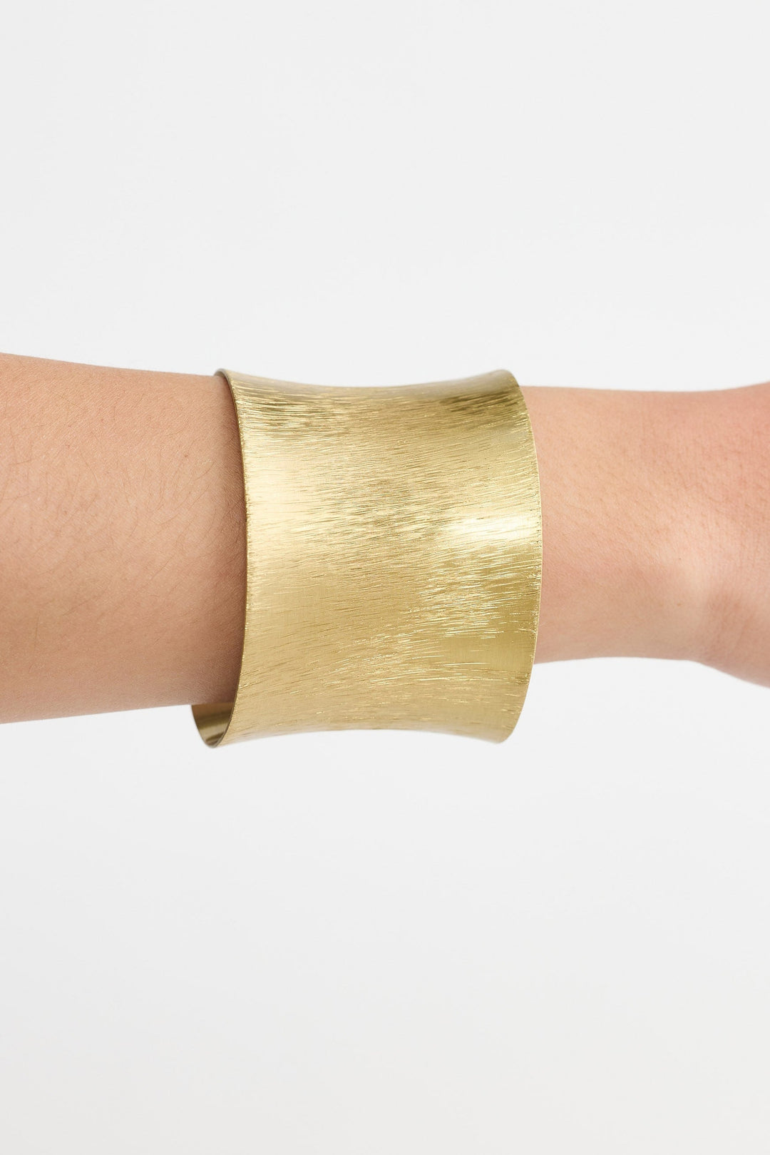 Gold bracelet on a wrist against a white background
