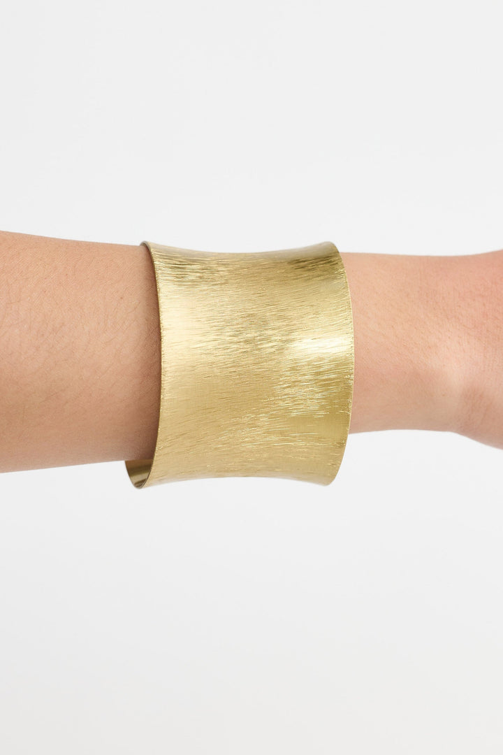 Gold bracelet on a wrist against a white background