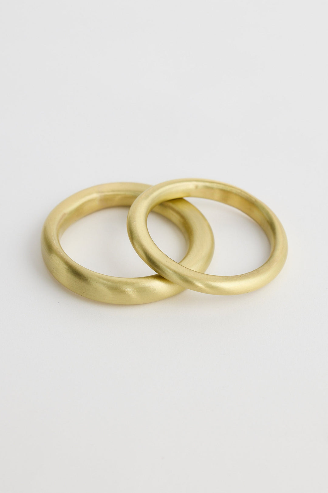 Two gold bangles on a light gray background