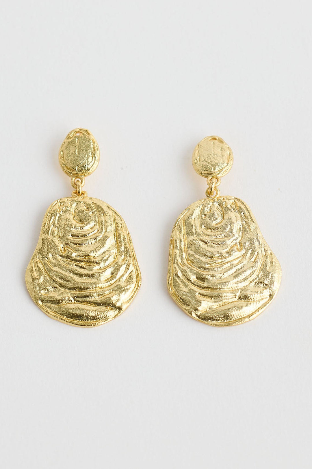 Close-up of gold oyster earrings earrings on white background.