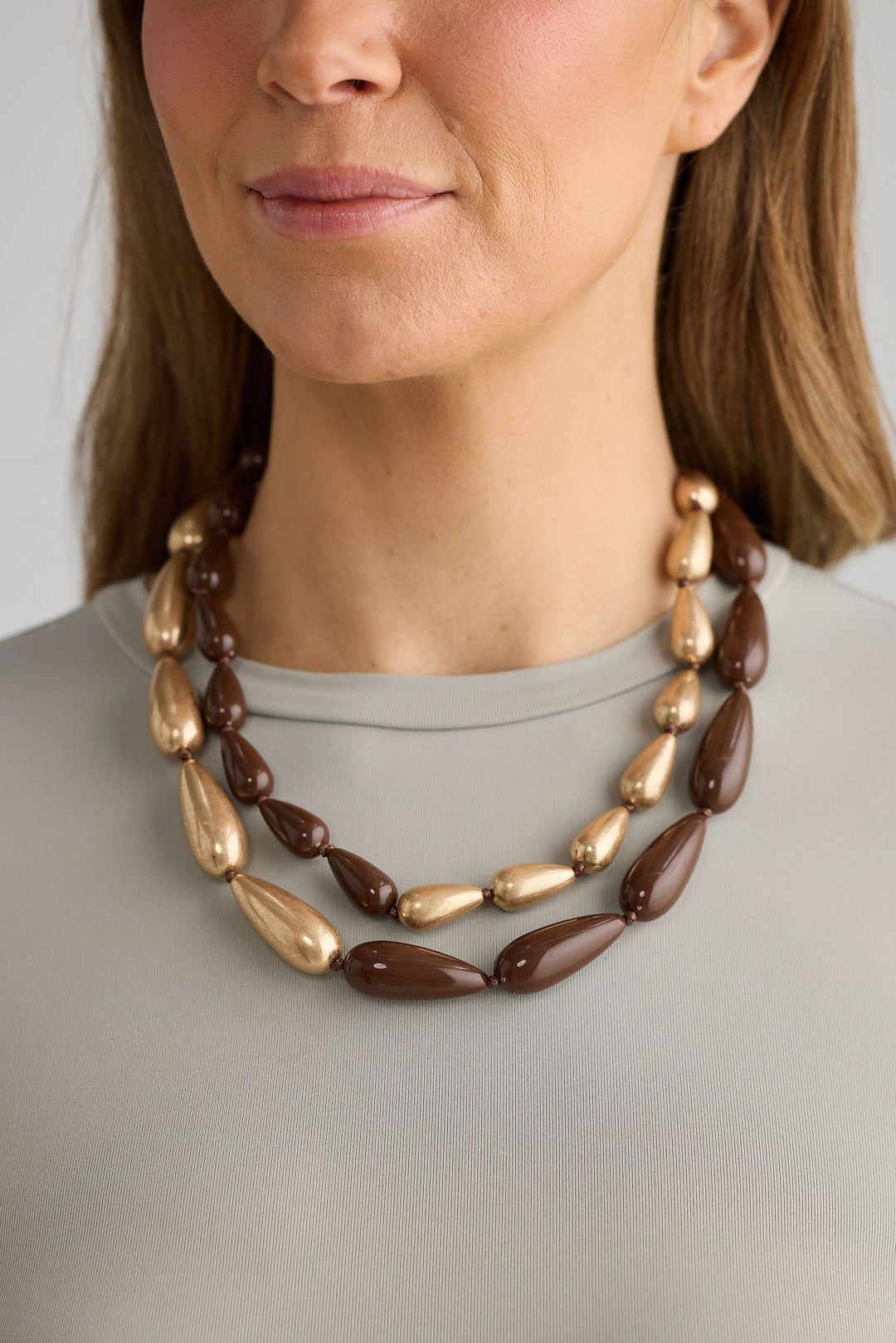 Close-up of wood w gold irina necklace necklace on white background.