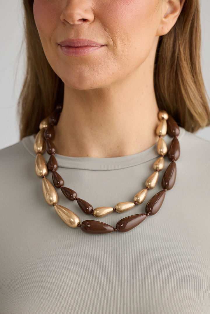 Close-up of wood w gold irina necklace necklace on white background.