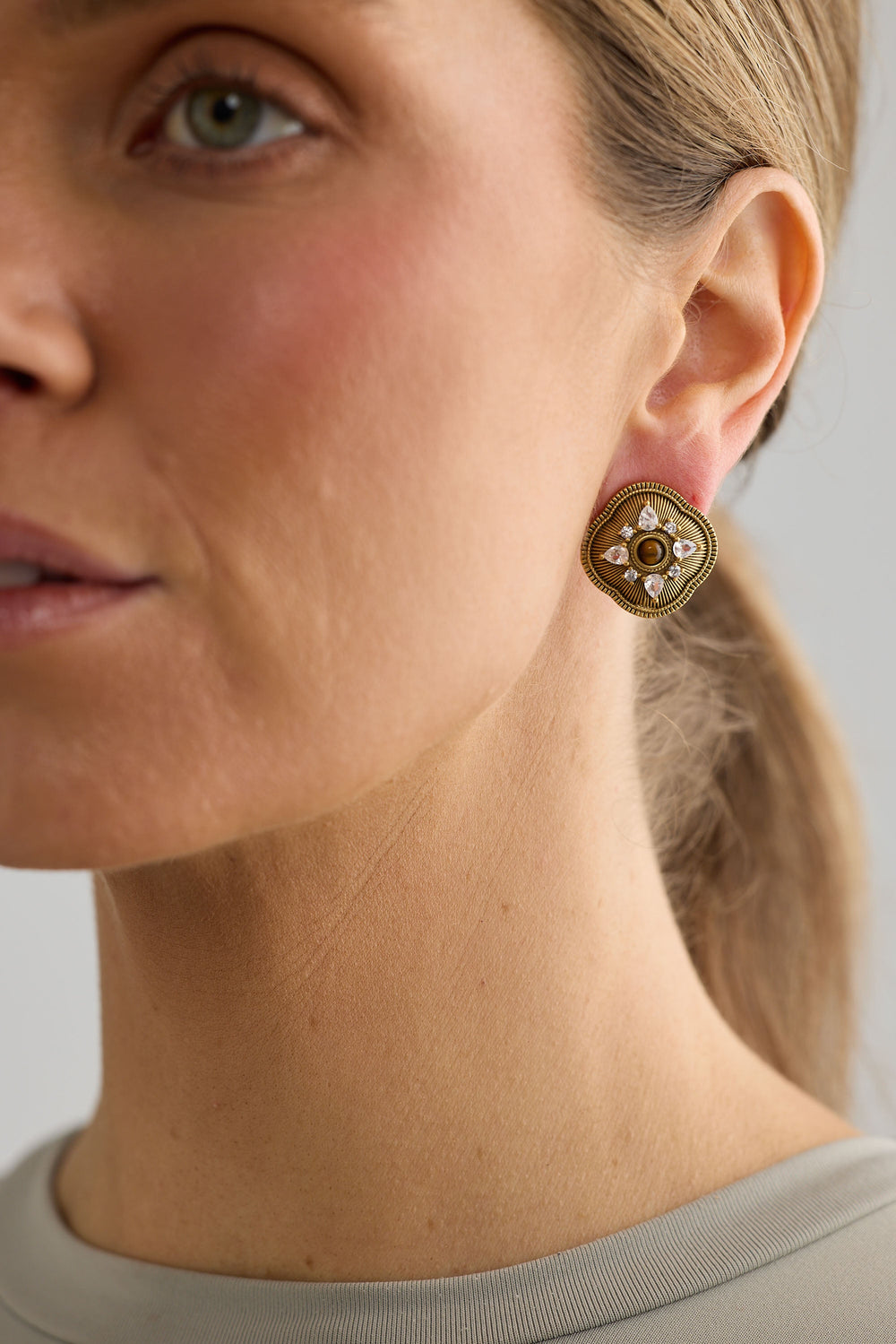 Close-up of gold quinn earrings earrings on white background.