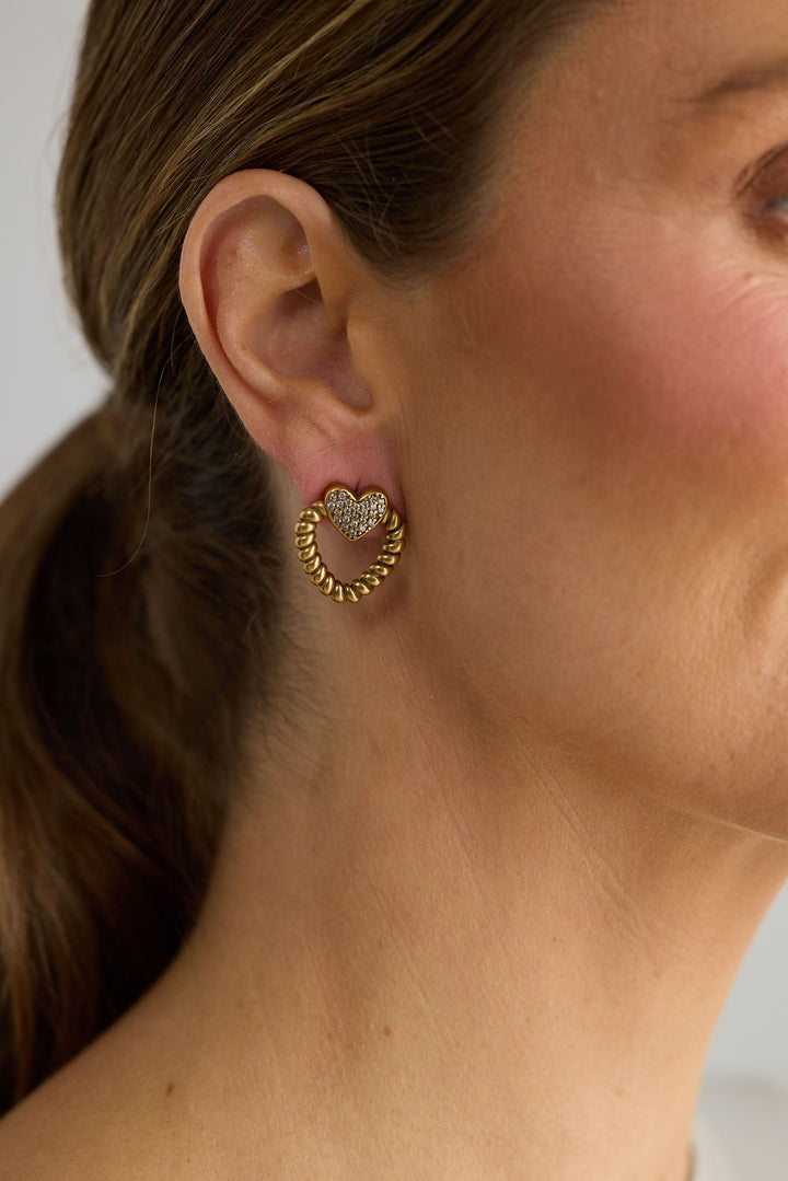 Close-up of gold charlie earrings earrings on white background.