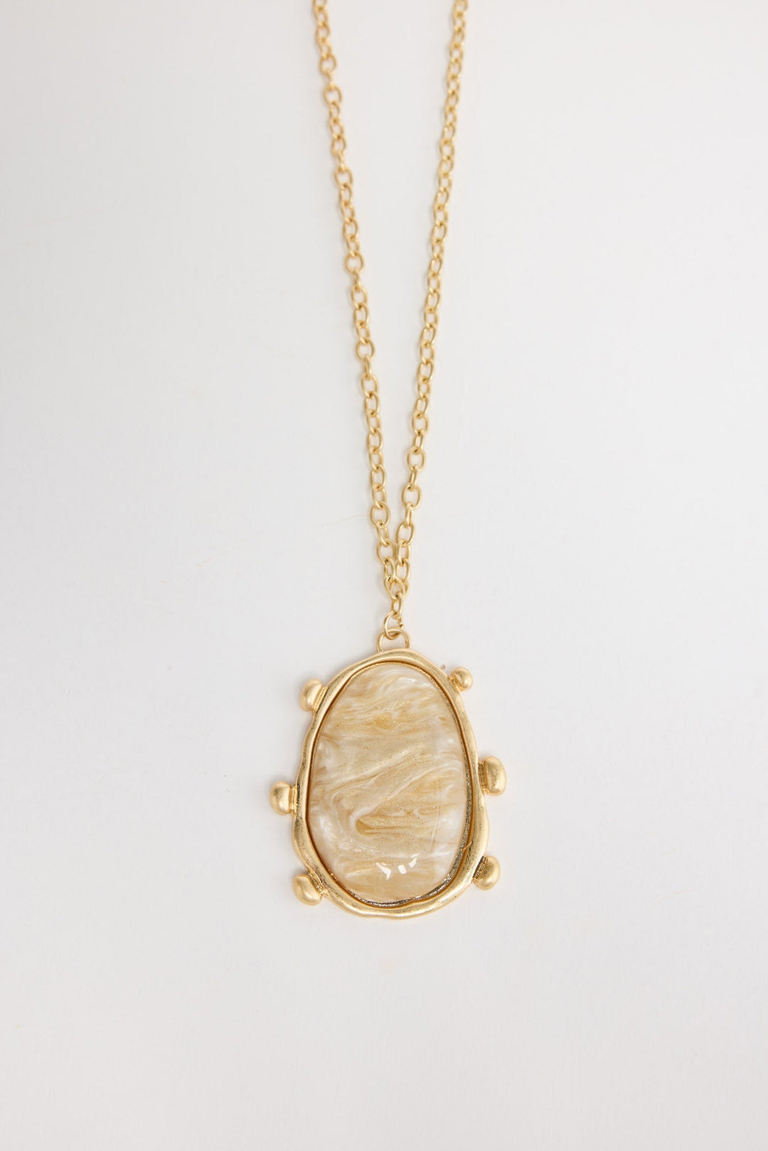 Gold-tone chain necklace with a large oval cream mother-of-pearl resin pendant set in a wide hammered bezel with small ball accents, shown flat on a white background