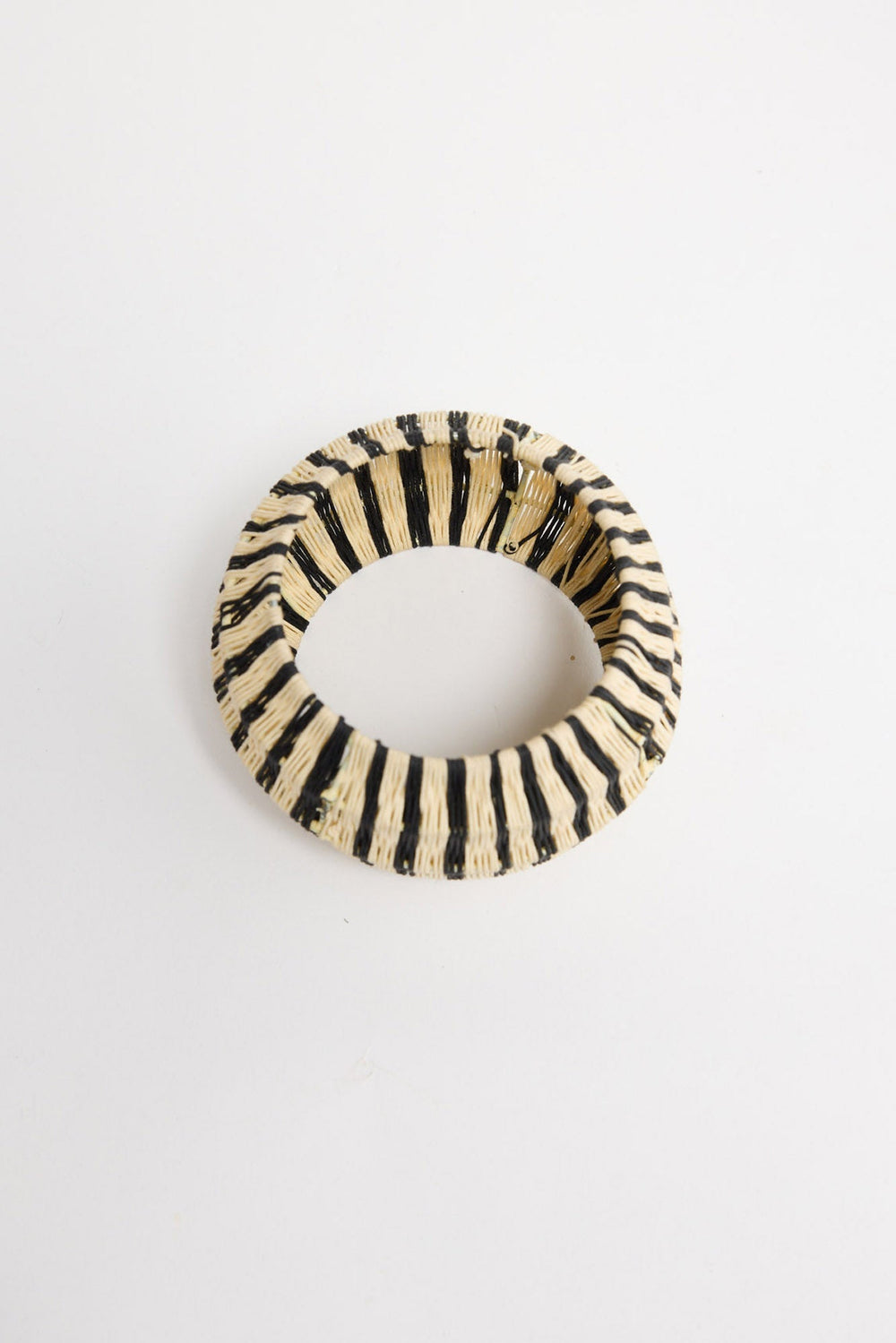 Angled view of the Lancer Bangle in Stripe showing the open bangle shape and cream-and-black striped weave