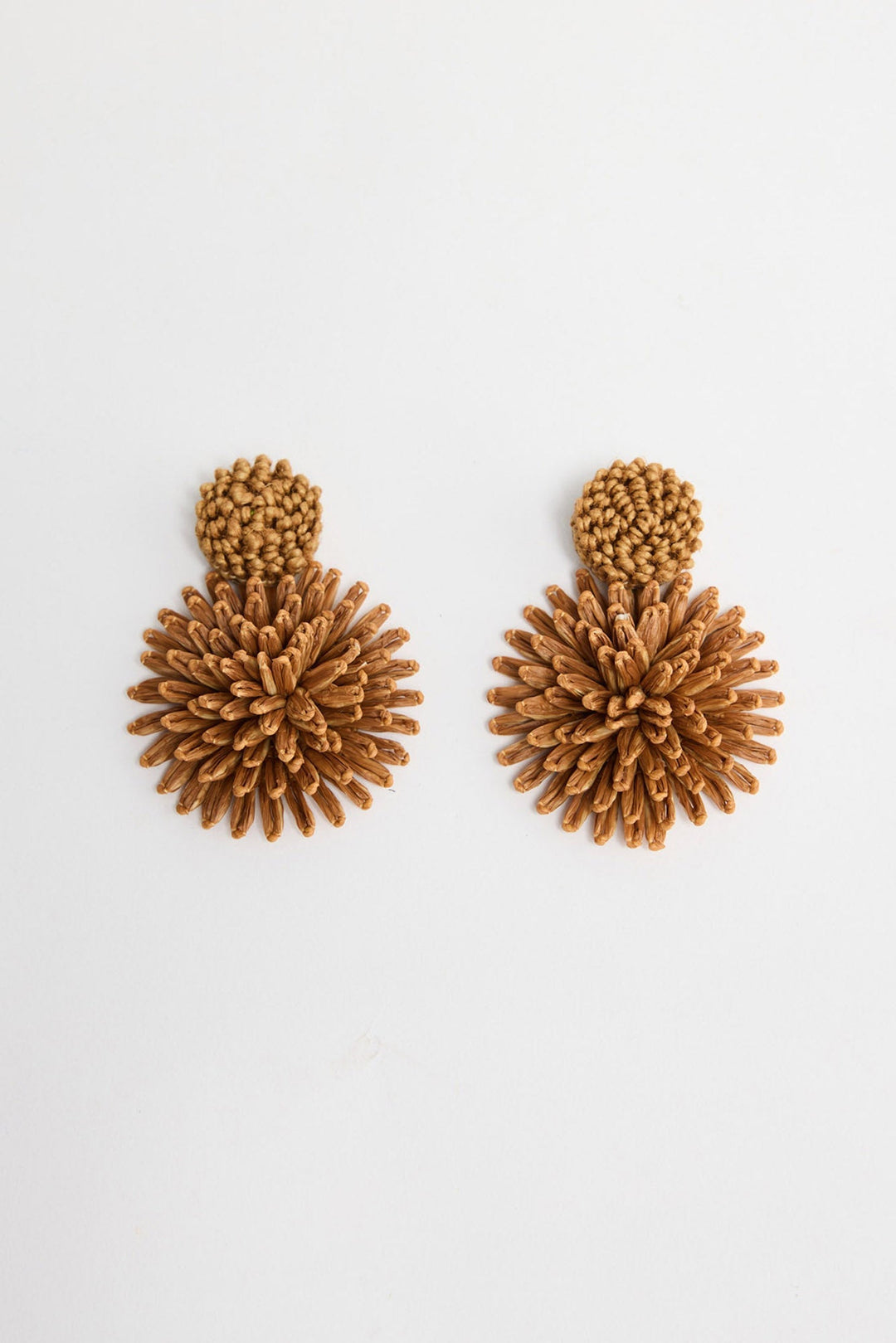 Pair of Polly statement earrings in Tan showing the woven raffia burst design and round textured stud on a white background