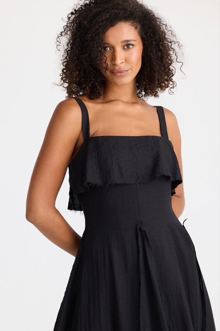 Woman wearing a black dress with ruffled top on a white background