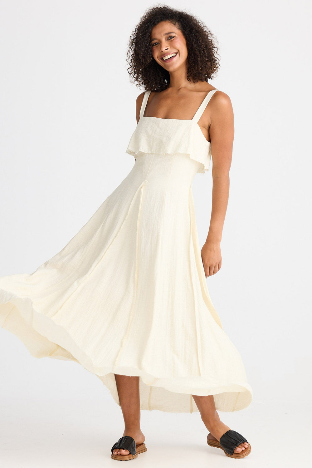 Woman wearing a white dress with straps and a ruffle on a white background