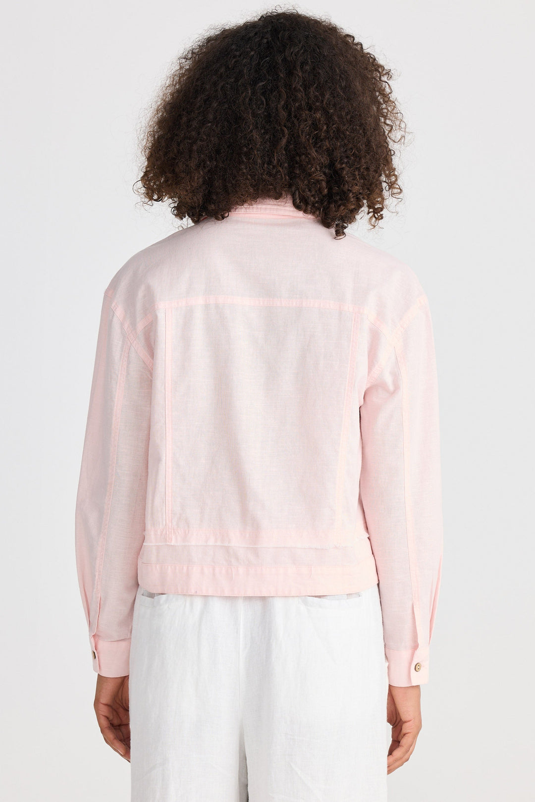 Person wearing a light pink jacket with long sleeves on a white background