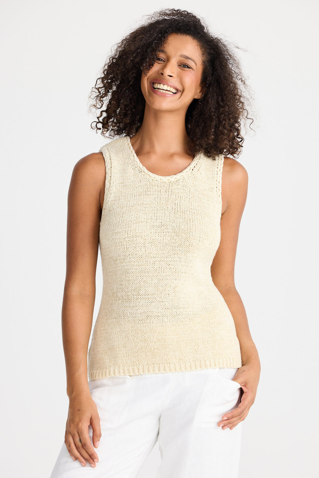 Woman wearing a beige sleeveless sweater against a white background
