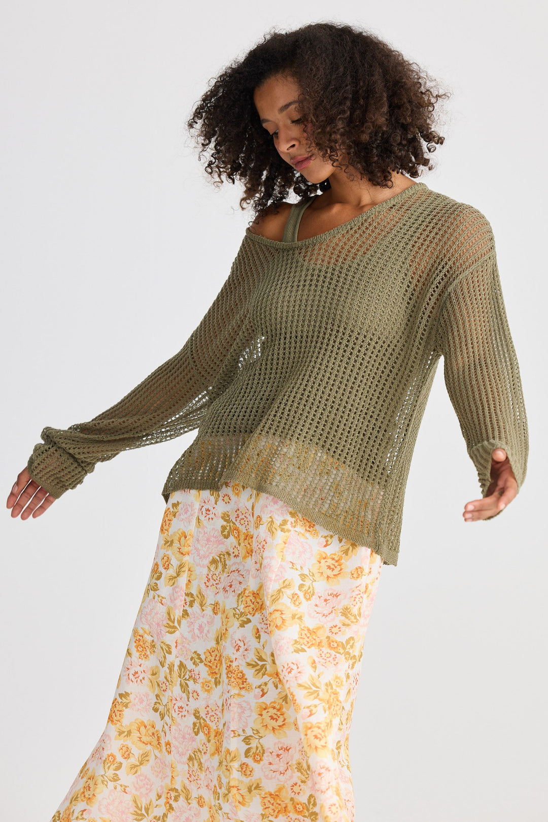 Woman wearing a green sweater and floral skirt on a white background