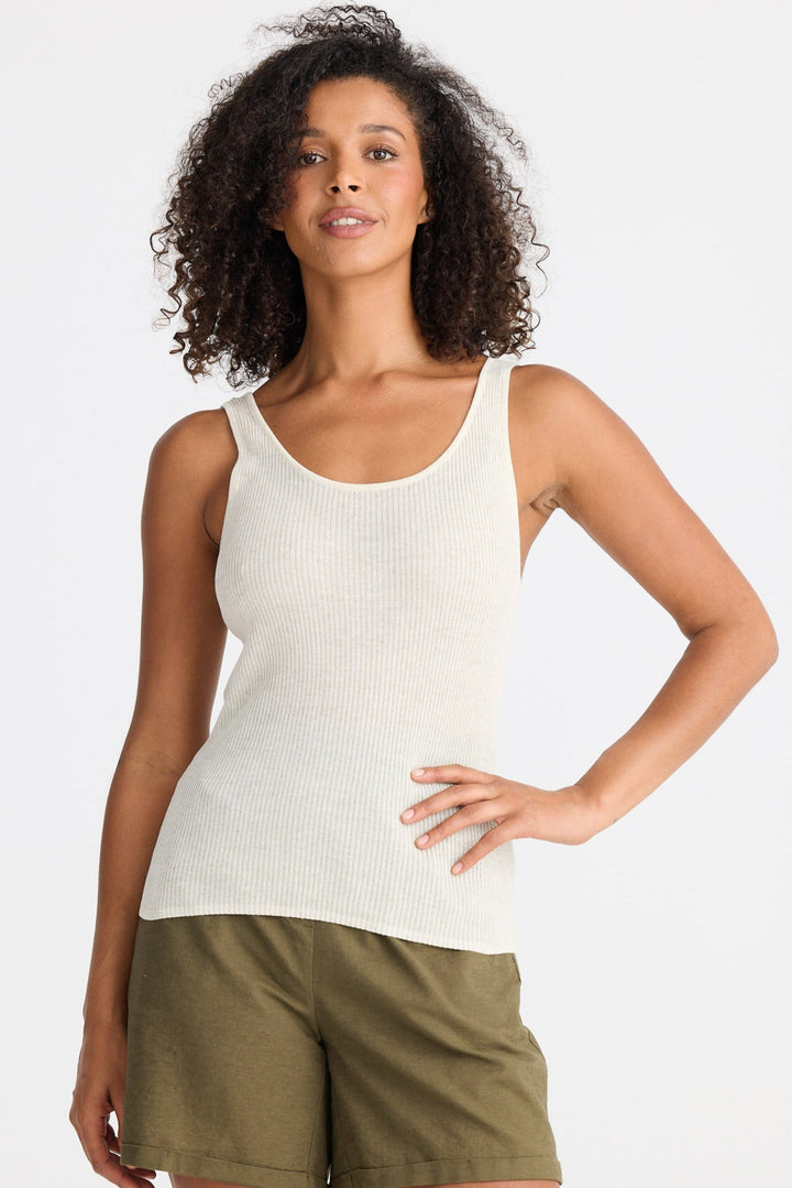 Woman wearing a white tank top and green shorts on a white background