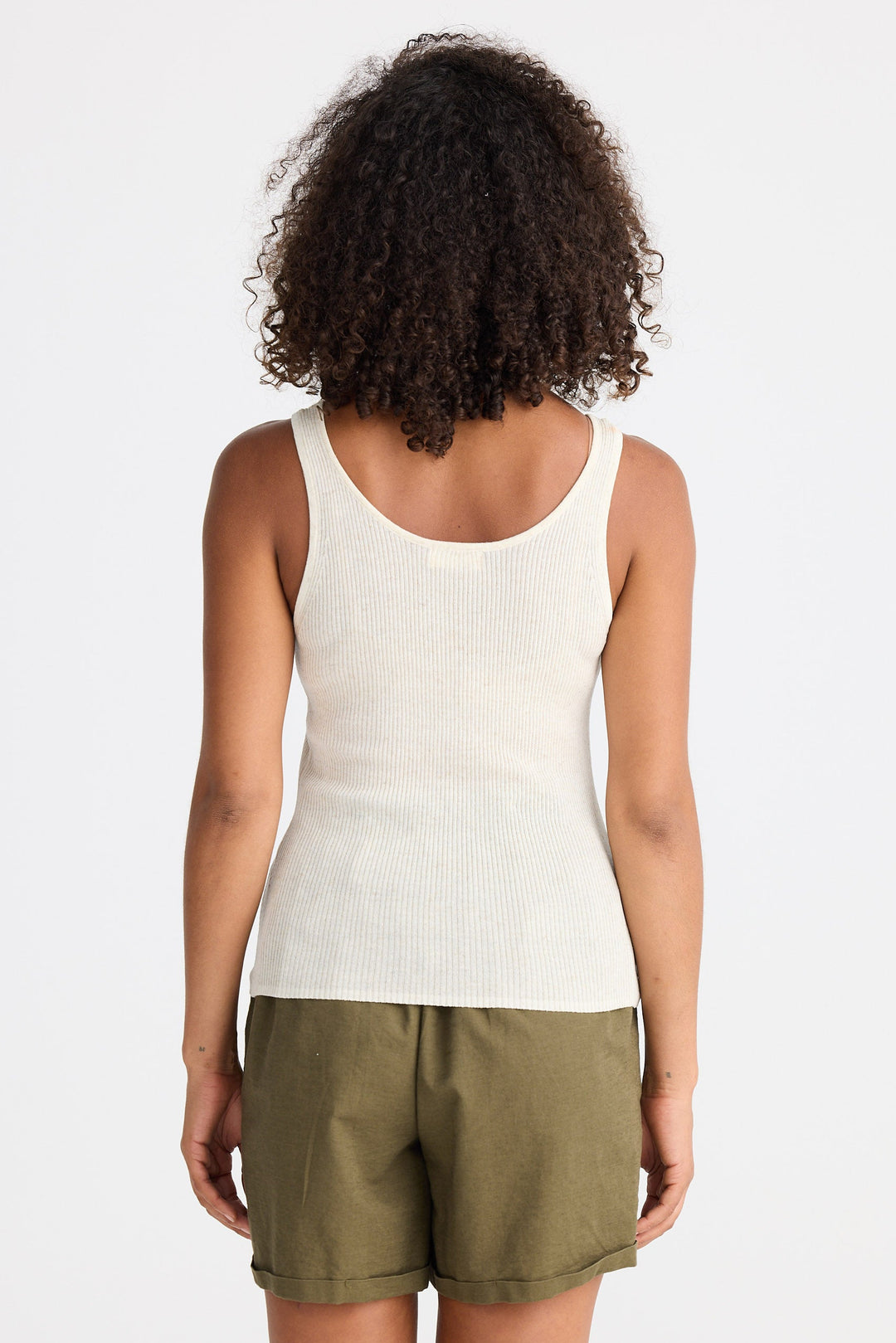 Person wearing a white tank top and green shorts on a plain background