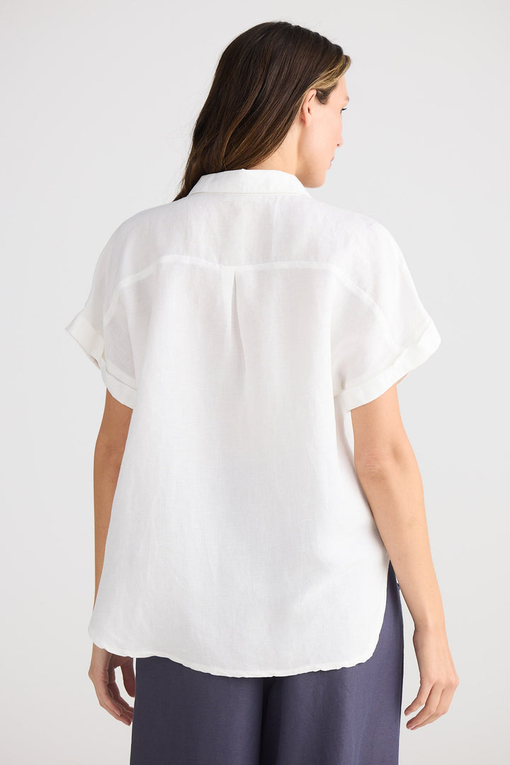 Woman wearing a white blouse and dark pants on a plain background