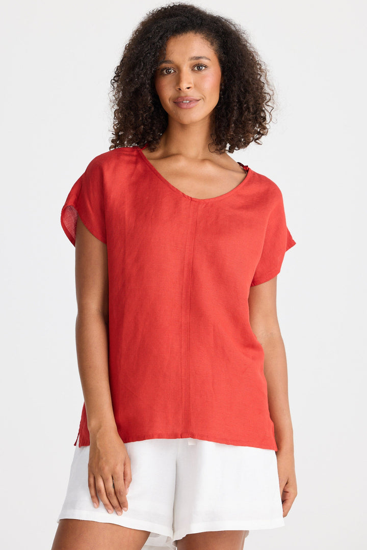 Woman wearing a red top and white shorts on a white background