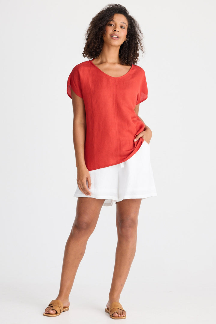 Woman wearing a red top and white shorts on a white background