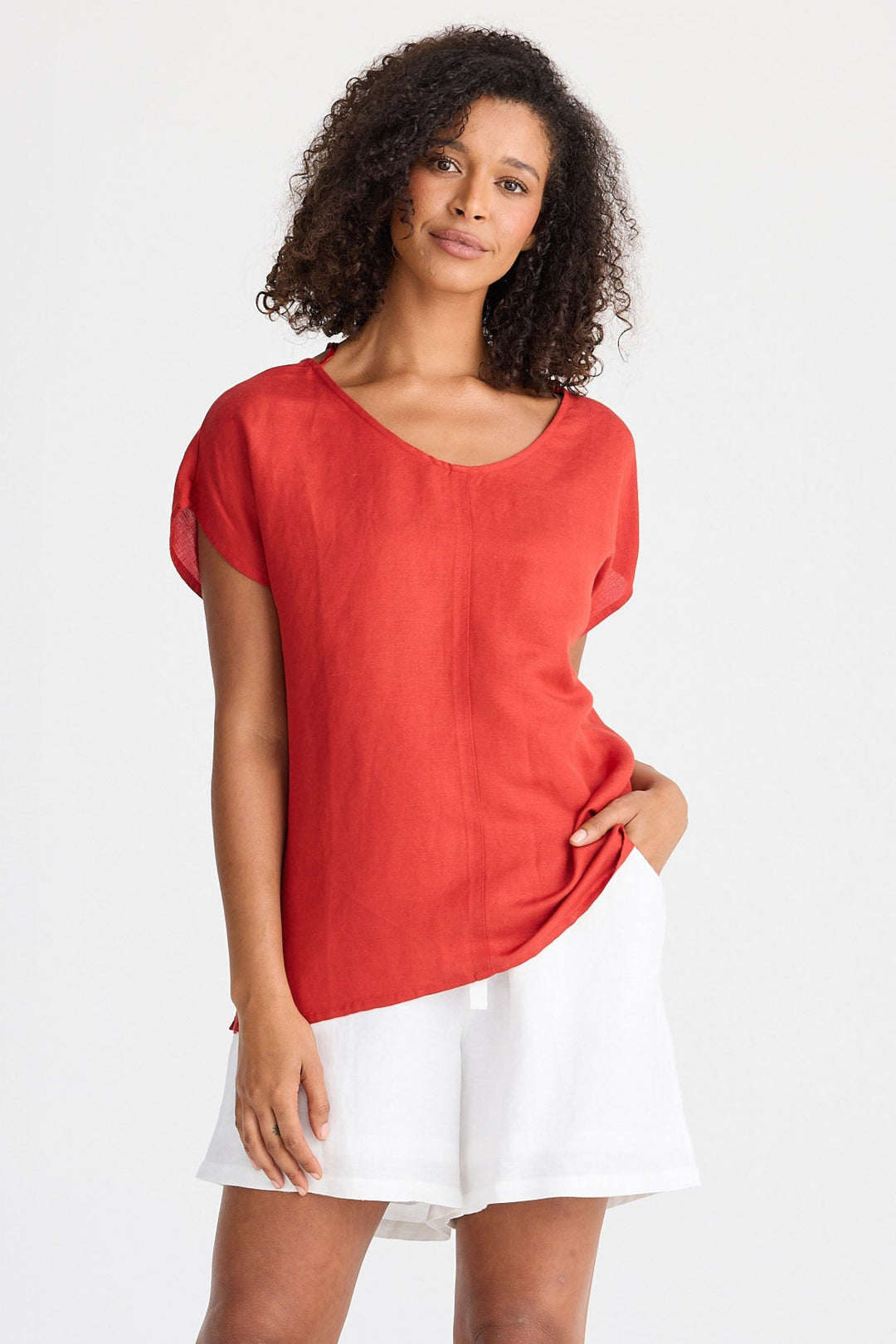 Woman wearing a red top and white shorts on a white background