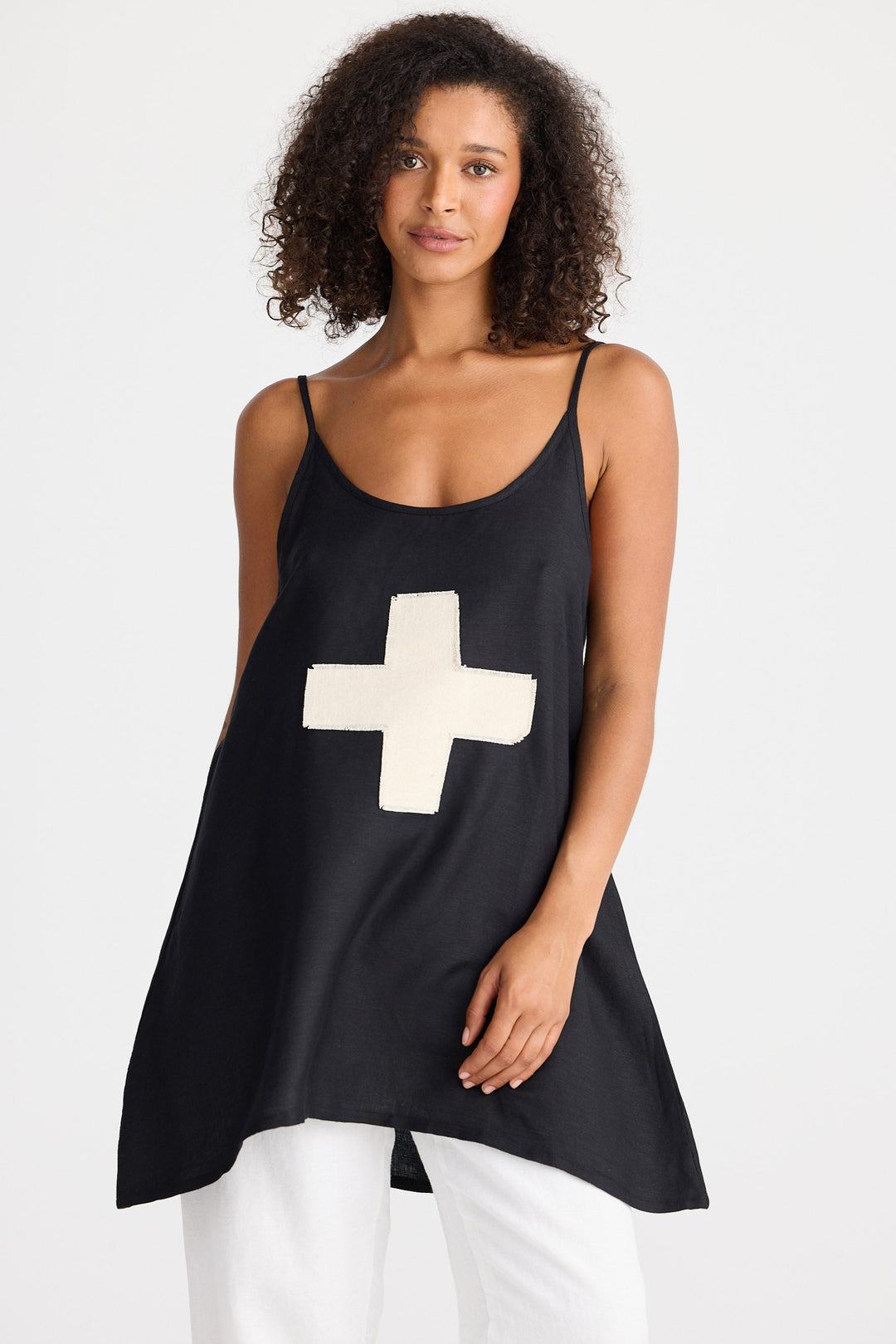 Woman wearing a black tank top with a cream cross on a white background