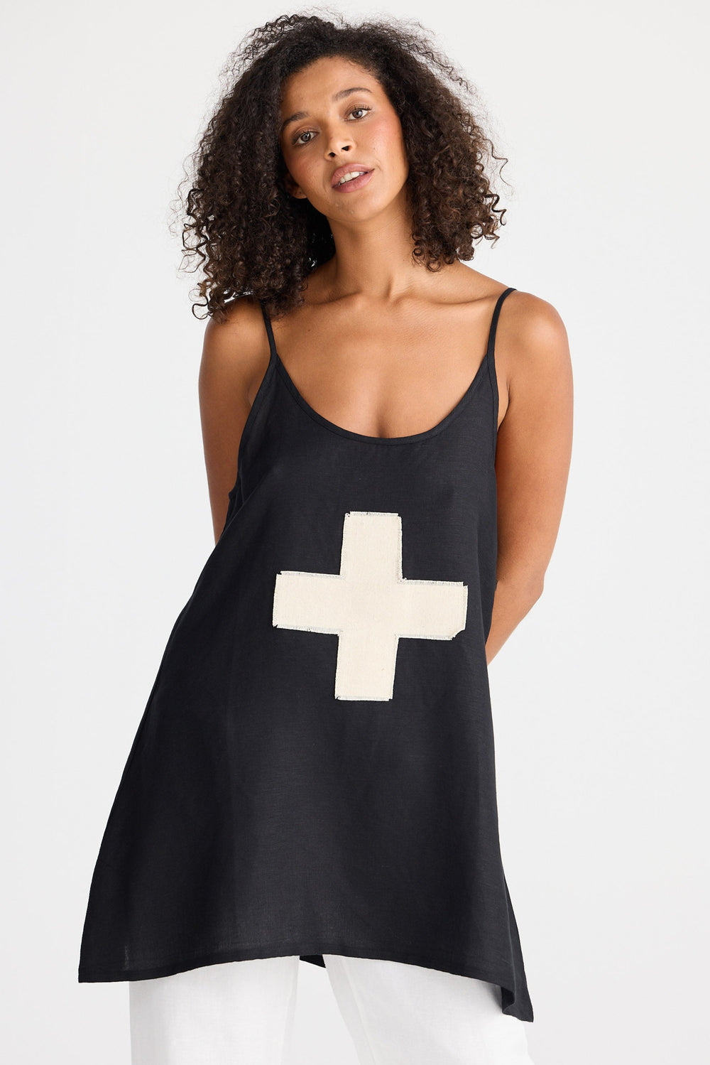 Woman wearing a black tank top with a cream cross on a white background