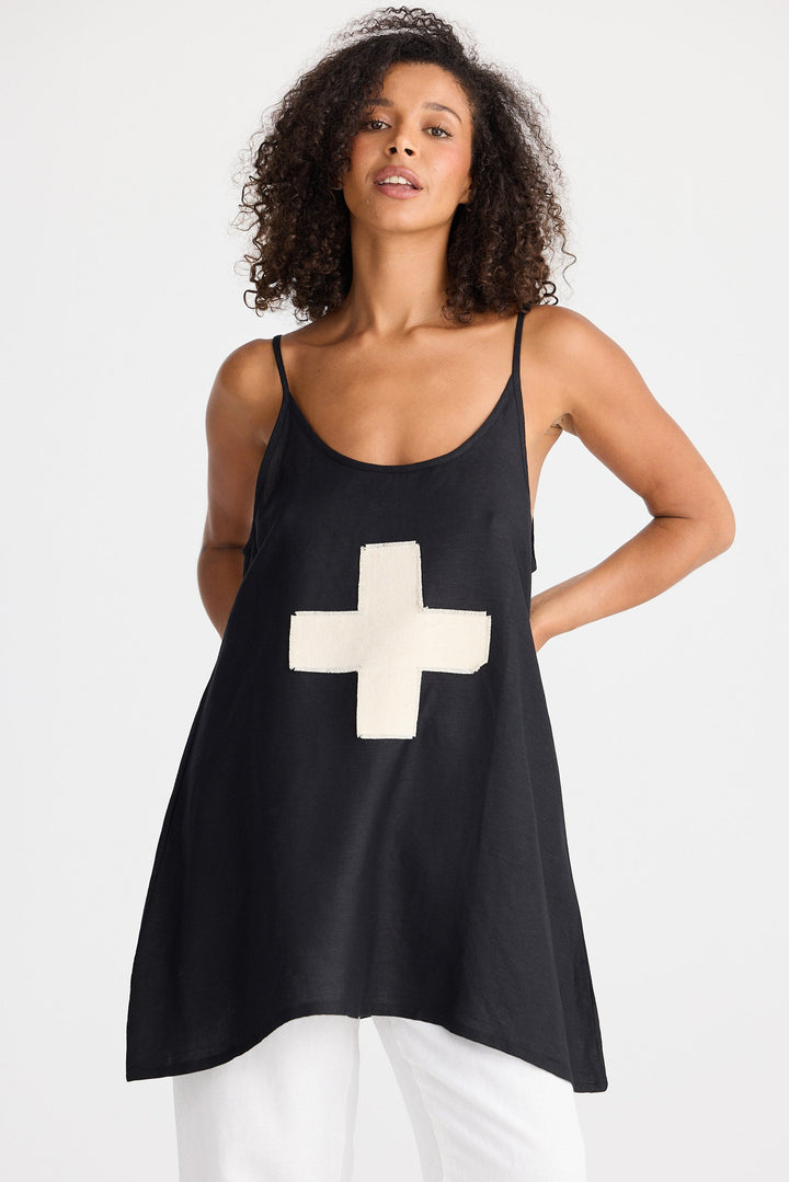 Woman wearing a black tank top with a cream cross design on a white background
