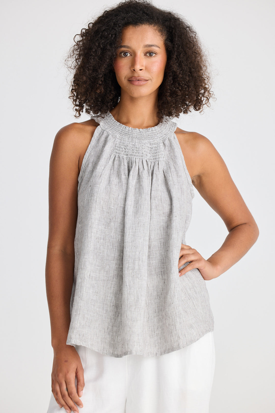 Woman wearing a gray sleeveless top with a white background