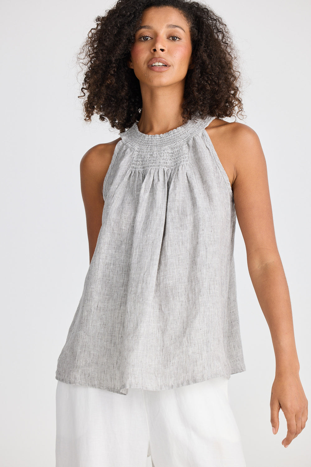 Woman wearing a gray sleeveless top with a white background