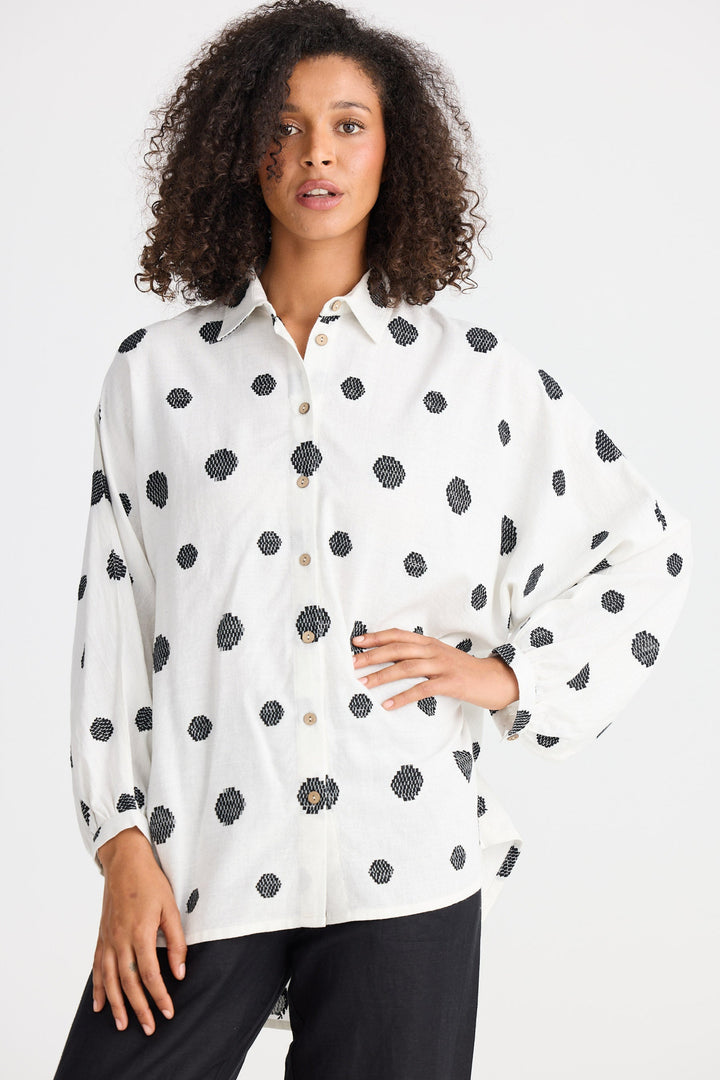 Woman wearing a polka dot shirt against a white background.