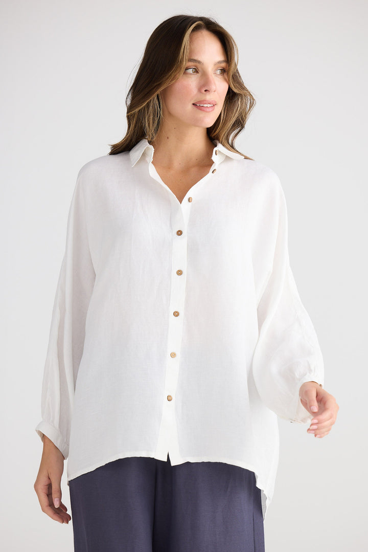 Woman wearing a white shirt and navy pants on a white background