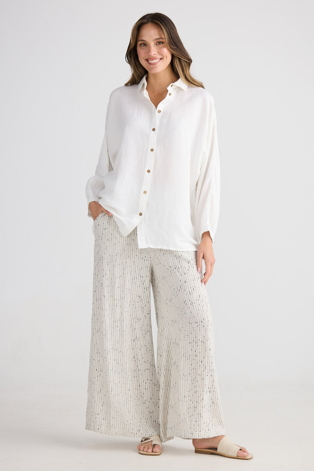 Woman wearing a white blouse and light-colored pants on a white background